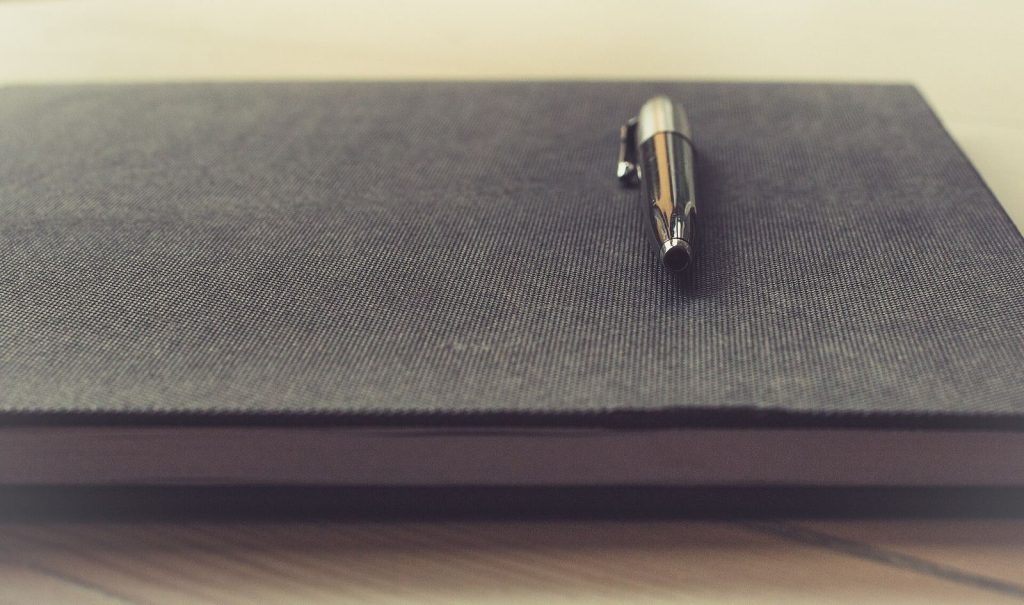 Pen resting on an open notebook for budgeting notes