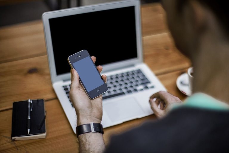 Person checking a rental listing on a smartphone and laptop