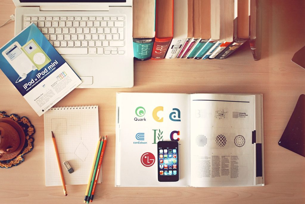 Books, pencils, laptop, and iphone on a desk (Unsplash)