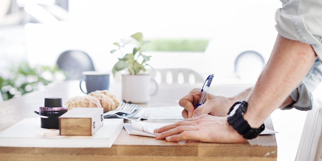 Man writing while standing (Unsplash)